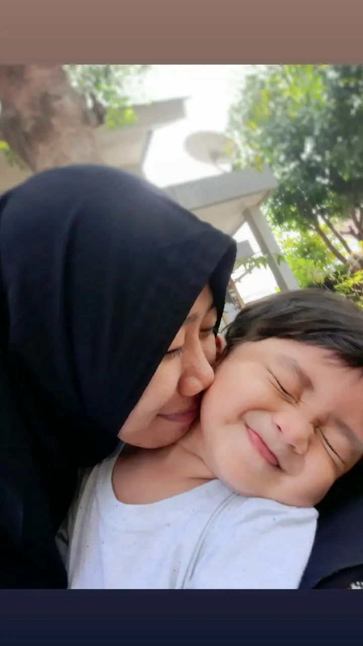 Ibu mencium pipi anaknya dengan penuh kasih