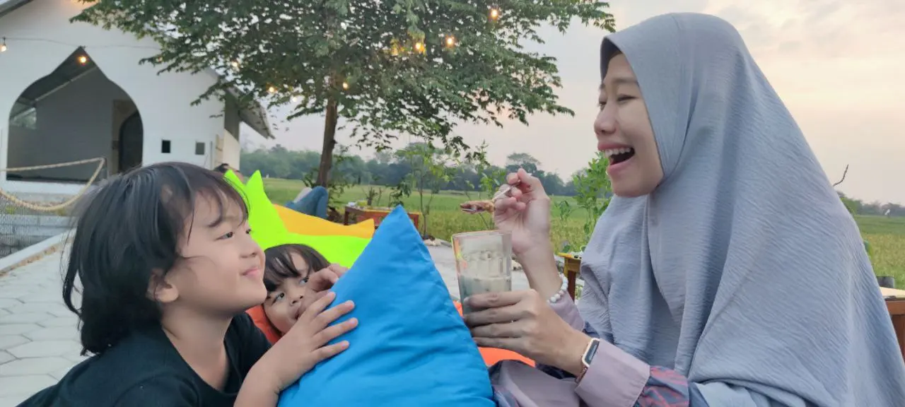 Ibu tertawa bersama anak-anak di ruang terbuka