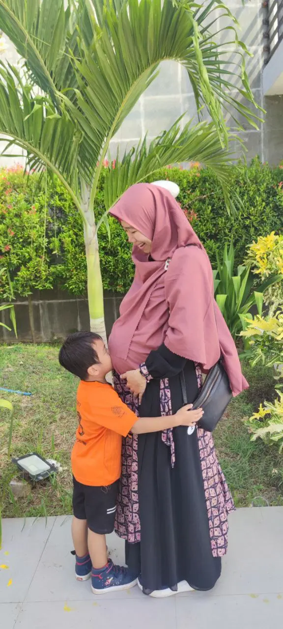 Seorang anak memeluk ibunya yang sedang hamil