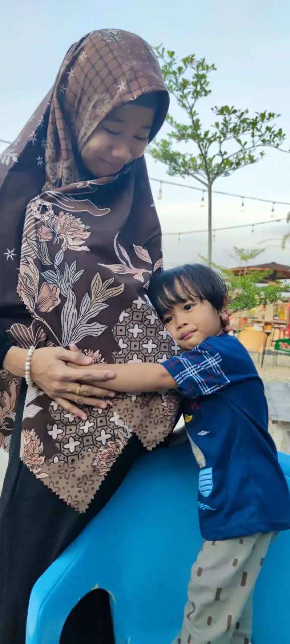 Anak memeluk ibunya yang sedang hamil